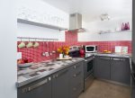 Newly-renovated kitchen with easy touch close cabinets and a vibrant red tile back splash